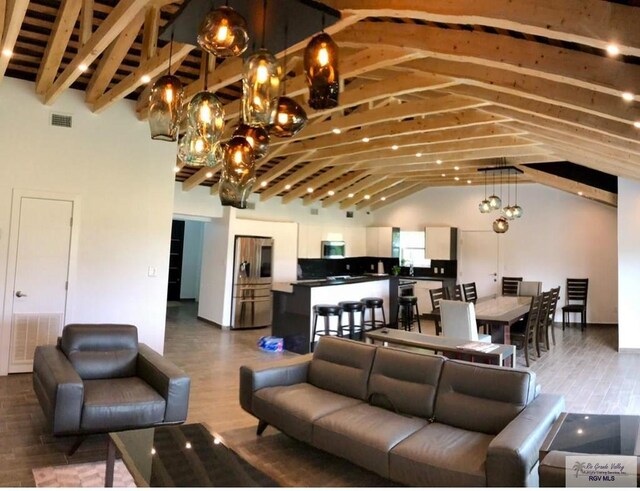 living room with wood-type flooring, high vaulted ceiling, an inviting chandelier, and beam ceiling