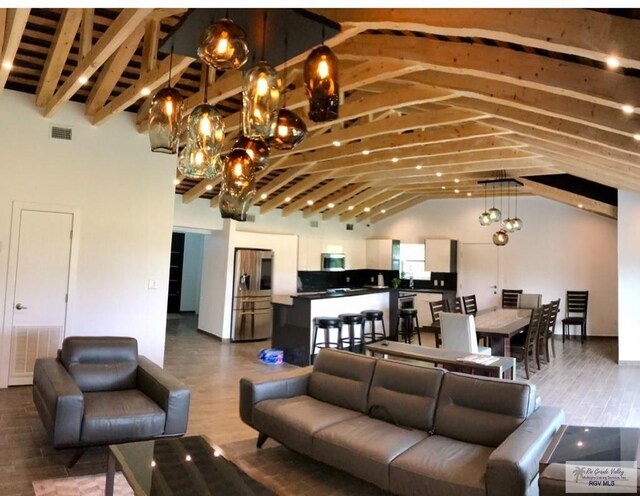 living room with wood-type flooring, high vaulted ceiling, an inviting chandelier, and beam ceiling