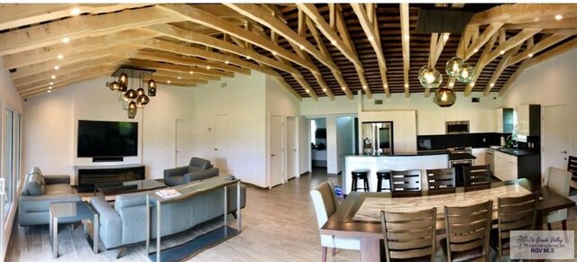 living room with a chandelier, vaulted ceiling, light hardwood / wood-style flooring, and sink