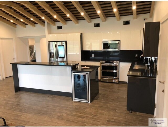 kitchen featuring white cabinetry, beamed ceiling, a kitchen island, and stainless steel appliances