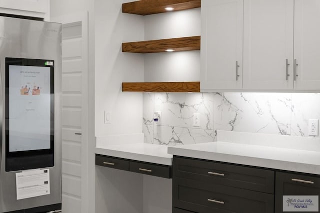 kitchen featuring white cabinetry, backsplash, and stainless steel refrigerator