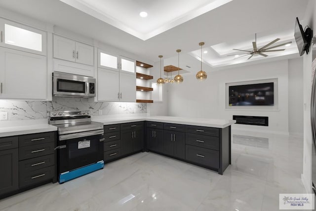 kitchen featuring white cabinetry, ceiling fan, hanging light fixtures, stainless steel appliances, and a tray ceiling