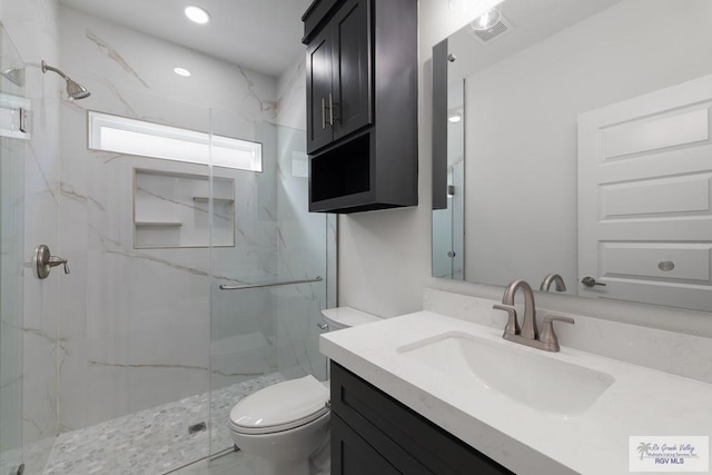 bathroom featuring a shower with door, vanity, and toilet