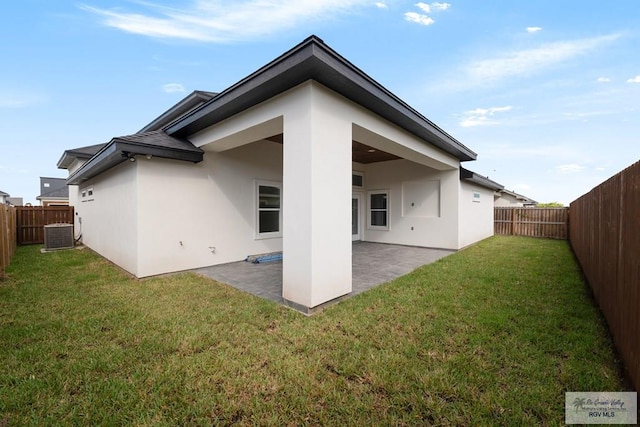 rear view of house featuring a lawn, cooling unit, and a patio