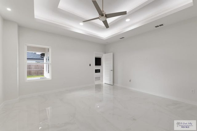 spare room featuring a tray ceiling and ceiling fan