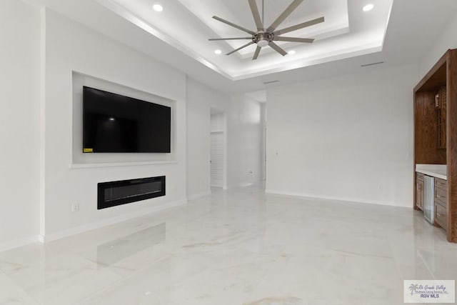 unfurnished living room with a tray ceiling and ceiling fan