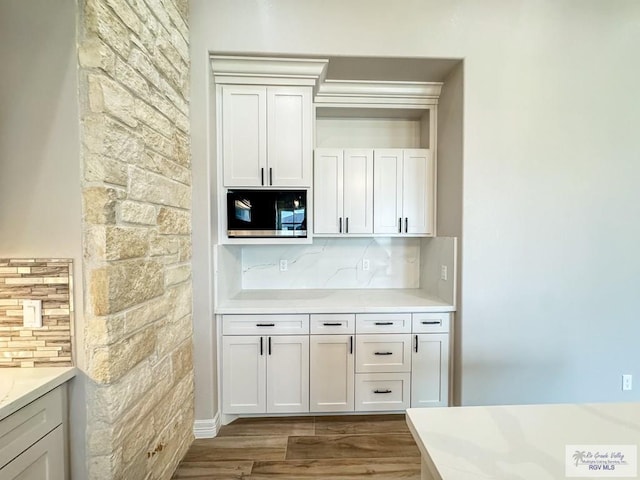 kitchen featuring backsplash, white cabinets, and wood-type flooring