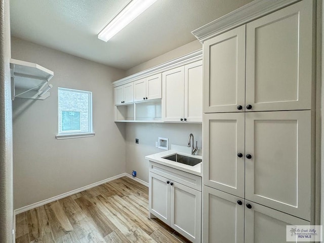 laundry area featuring hookup for an electric dryer, washer hookup, cabinets, sink, and light hardwood / wood-style flooring