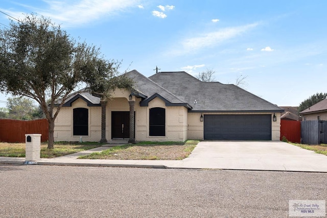 view of front of property with a garage, concrete driveway, brick siding, and fence