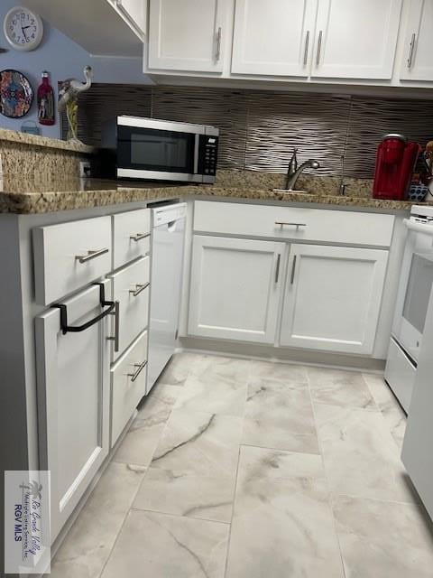 kitchen with tasteful backsplash, sink, white cabinets, dark stone counters, and white appliances