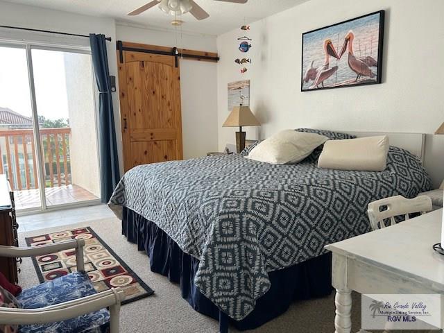 bedroom featuring access to exterior, a barn door, and ceiling fan