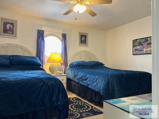 bedroom with ceiling fan, carpet floors, and a textured ceiling