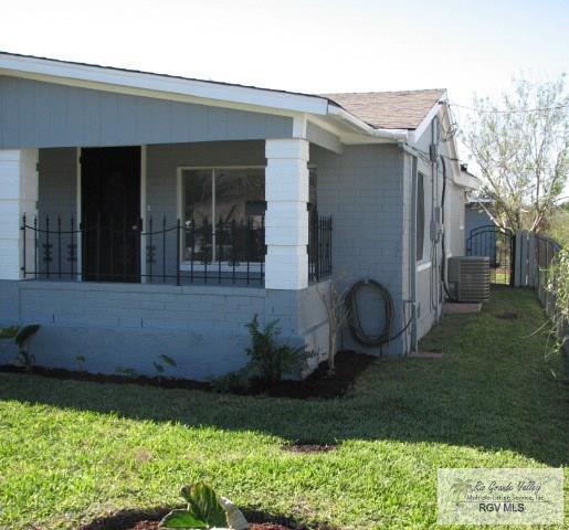 view of side of property featuring a lawn, fence, and central AC unit