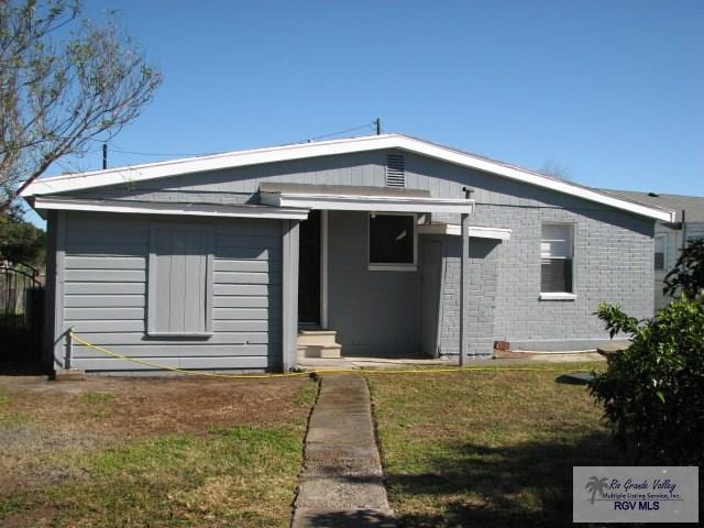 back of property featuring brick siding and a yard