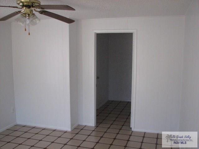 empty room with ceiling fan and a textured ceiling