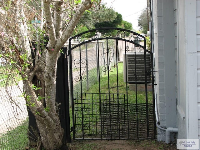 view of gate featuring a lawn and cooling unit