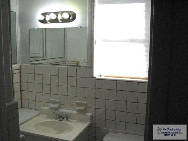 bathroom with vanity, toilet, and tile walls