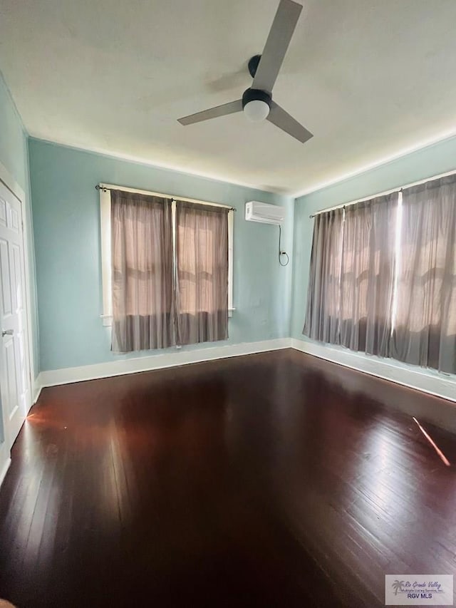 unfurnished room with a wall unit AC, ceiling fan, and dark wood-type flooring