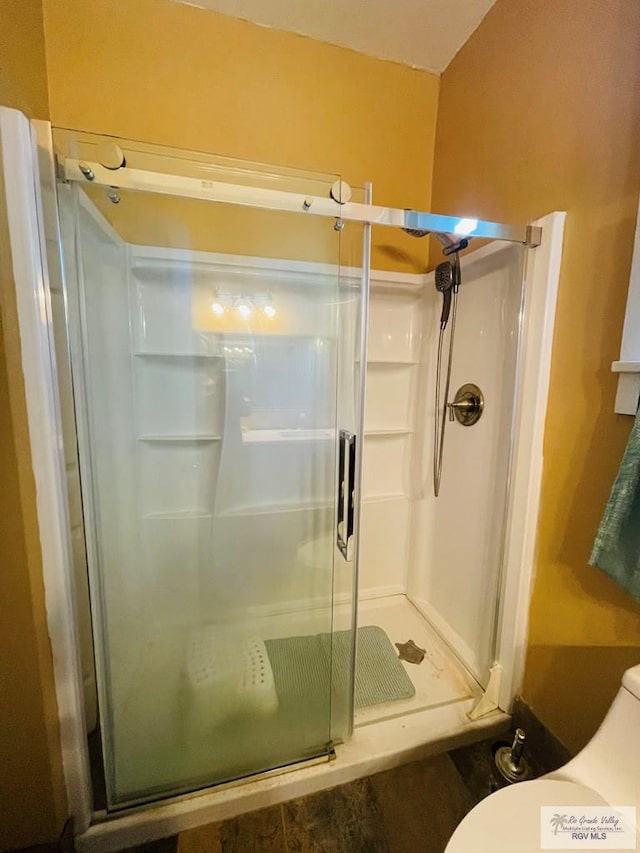 bathroom featuring toilet and an enclosed shower