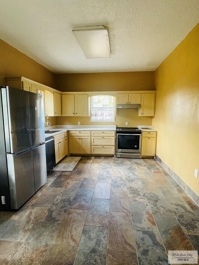 kitchen featuring light brown cabinets, a textured ceiling, stainless steel appliances, and sink