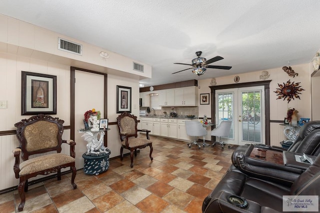 living room with ceiling fan, french doors, and a textured ceiling