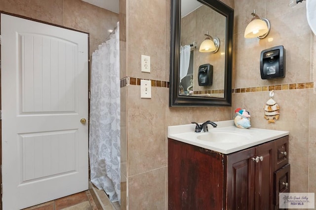 bathroom featuring tile patterned floors, vanity, tile walls, and walk in shower