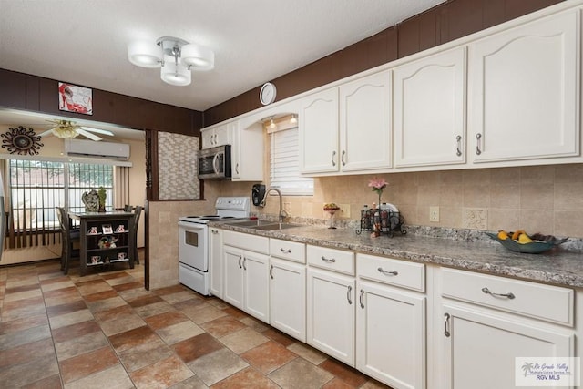 kitchen with white range with electric stovetop, ceiling fan, sink, an AC wall unit, and white cabinets