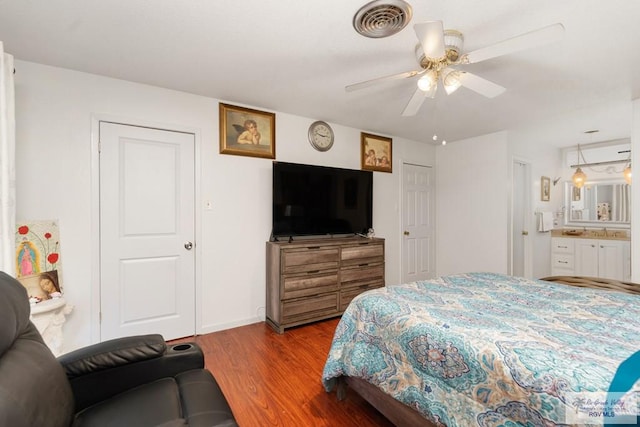 bedroom with hardwood / wood-style floors, ensuite bathroom, and ceiling fan