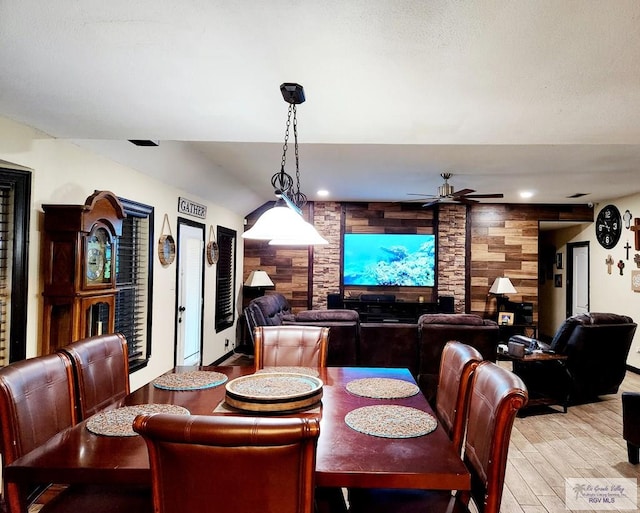 dining room with ceiling fan, wooden walls, and light hardwood / wood-style floors