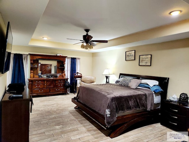 bedroom with ceiling fan and a raised ceiling