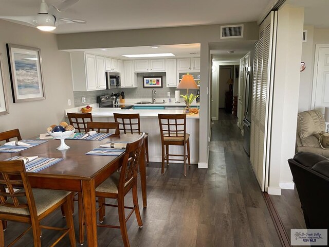 dining area with ceiling fan, visible vents, and dark wood finished floors