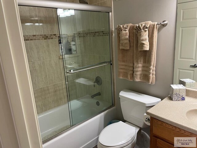 bathroom with enclosed tub / shower combo, vanity, and toilet