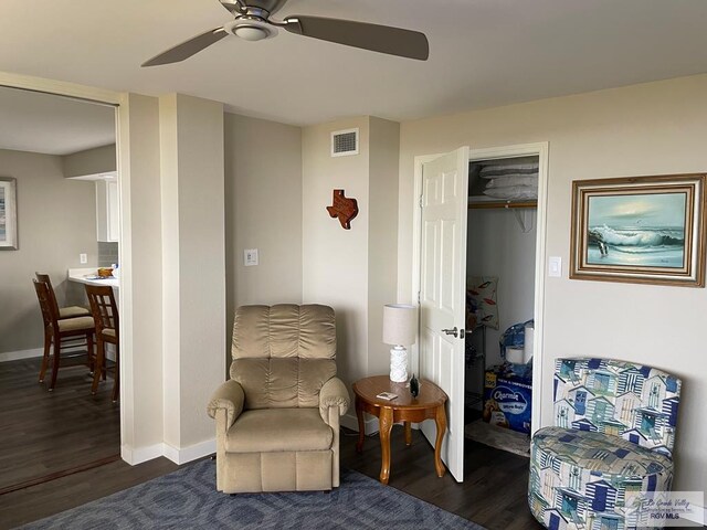 sitting room featuring a ceiling fan, visible vents, baseboards, and wood finished floors