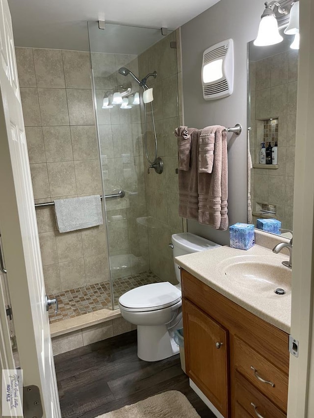 full bathroom with a stall shower, visible vents, toilet, wood finished floors, and vanity