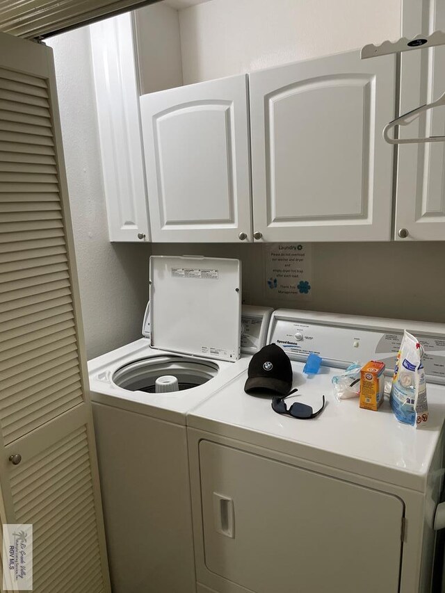 clothes washing area featuring cabinet space and separate washer and dryer