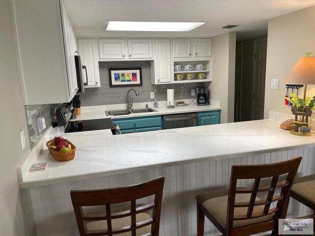 kitchen with a peninsula, a sink, visible vents, appliances with stainless steel finishes, and decorative backsplash