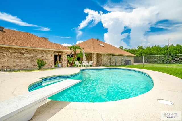 view of swimming pool featuring a patio, central AC unit, and a diving board