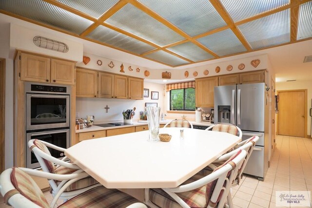 kitchen with a breakfast bar, light tile patterned floors, stainless steel appliances, and a kitchen island