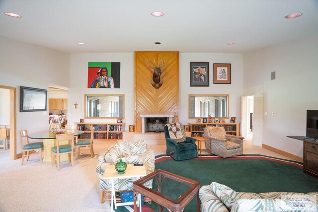 living room featuring a tiled fireplace, carpet floors, and a high ceiling