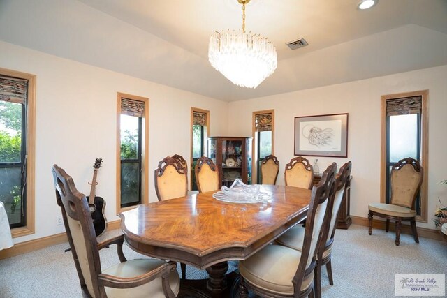 dining room featuring light carpet, vaulted ceiling, and a notable chandelier