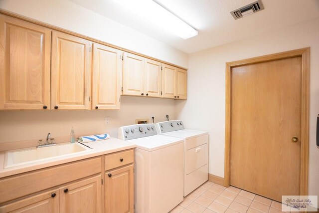 laundry room with sink, light tile patterned floors, cabinets, and independent washer and dryer