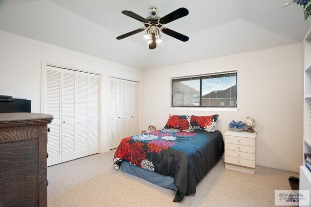 bedroom with ceiling fan, light colored carpet, and two closets