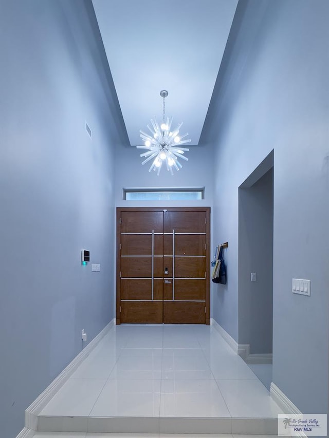 hall featuring baseboards, visible vents, a chandelier, and tile patterned flooring