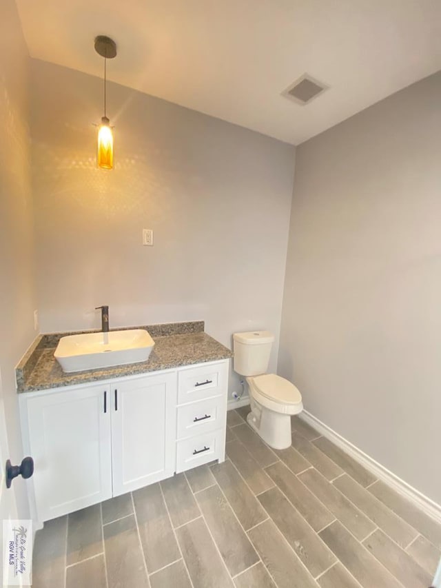 1271 Bridle Way, San Benito, TX 78586 - bathroom with wood tiled floors, toilet, baseboards, and vanity