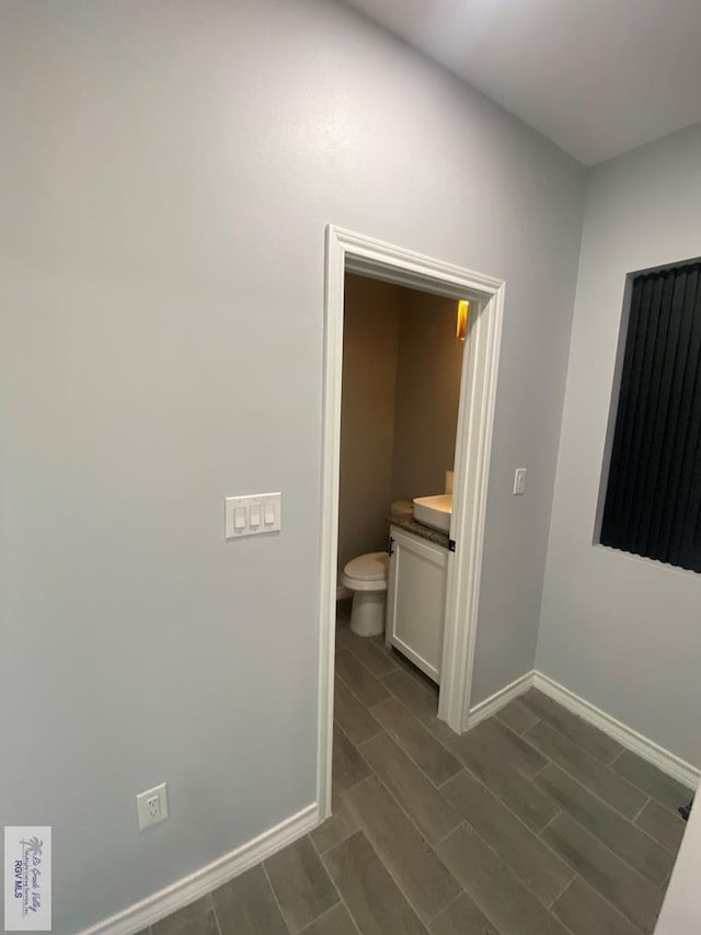 1271 Bridle Way, San Benito, TX 78586 - bathroom featuring baseboards, wood tiled floors, vanity, and toilet