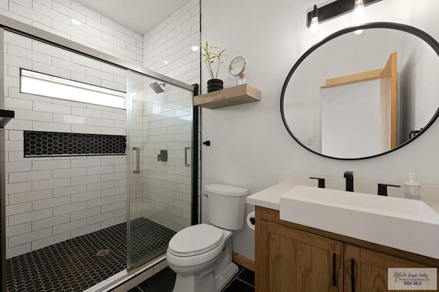 bathroom featuring vanity, toilet, and a shower with shower door