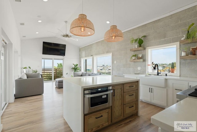 kitchen featuring lofted ceiling, white cabinetry, hanging light fixtures, and a wealth of natural light