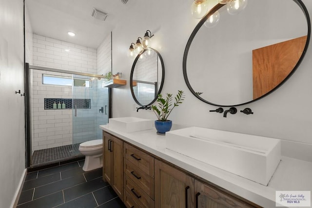 bathroom featuring tile patterned flooring, vanity, toilet, and an enclosed shower