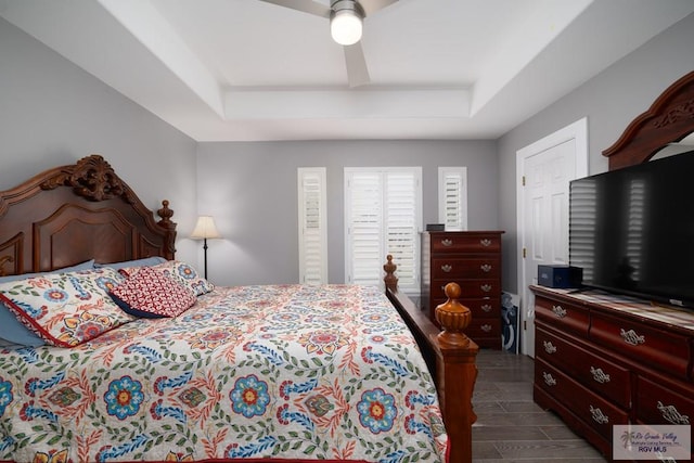 bedroom featuring wood tiled floor, a tray ceiling, and ceiling fan