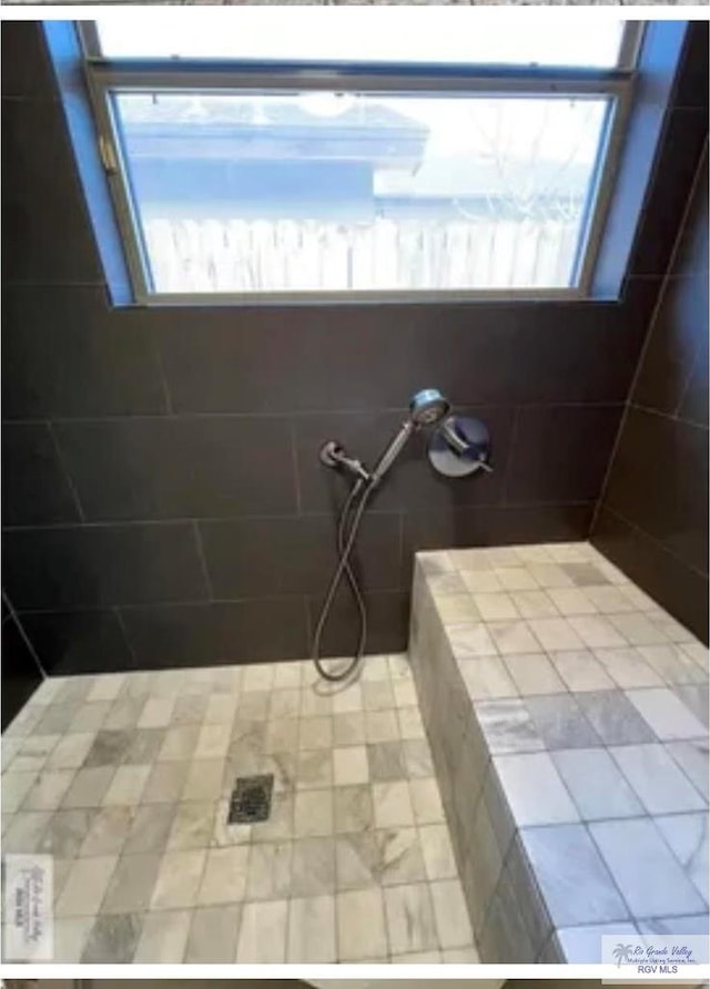 full bathroom featuring plenty of natural light and tiled shower